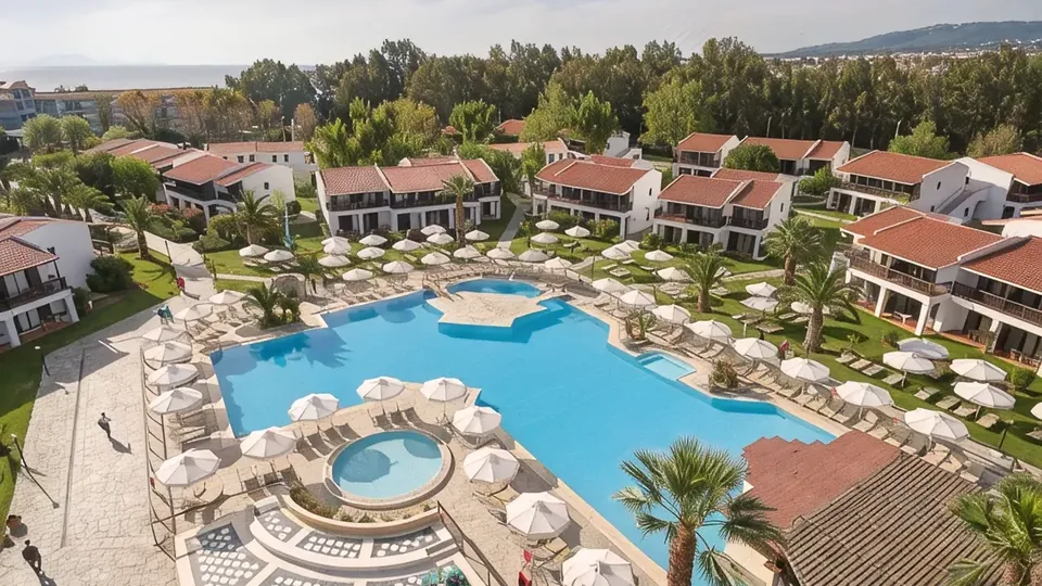 The Golden Coast resort pool ringed by parasols, with tile-roofed bungalows and palms behind
